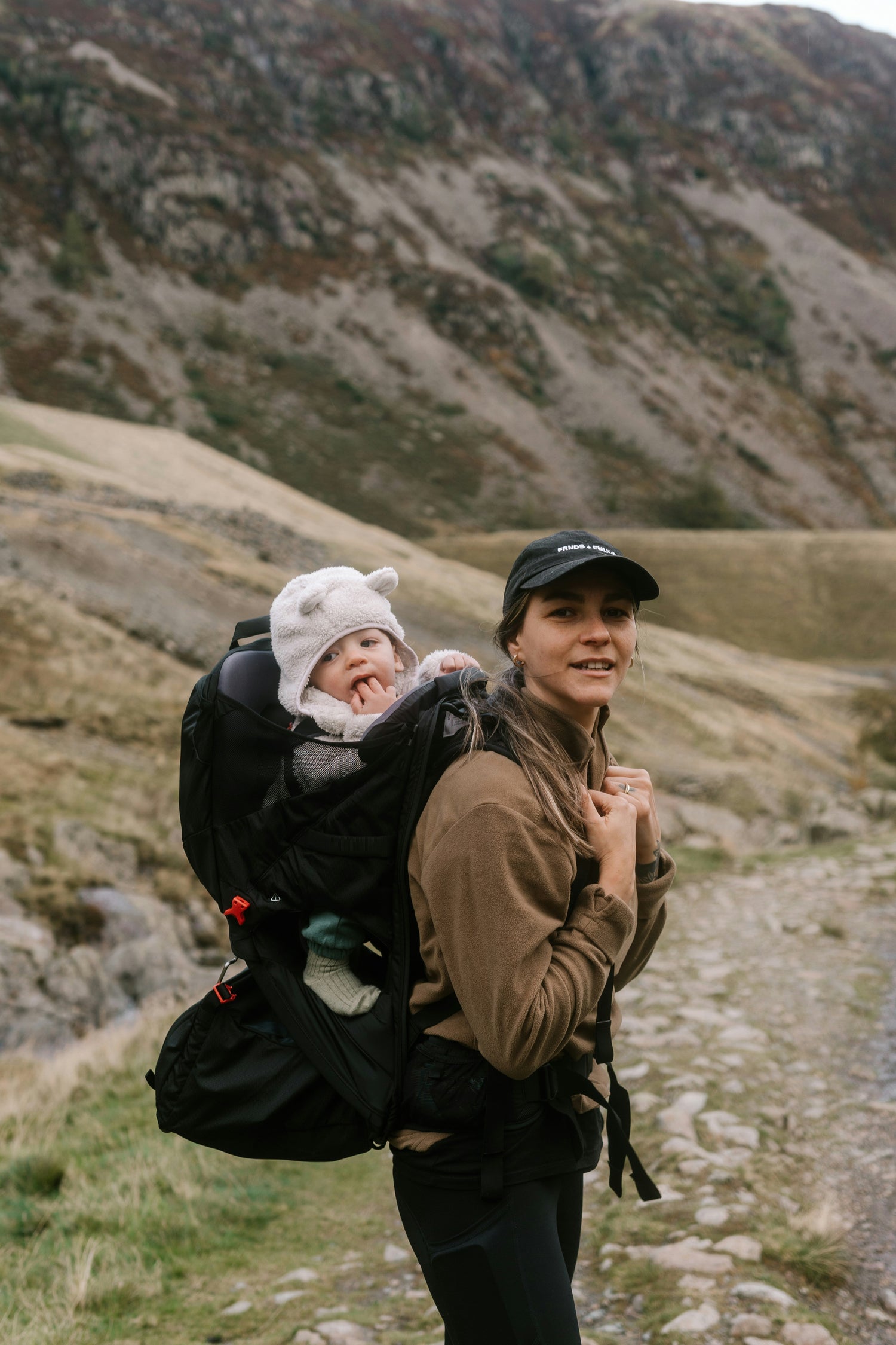 Femme en randonnée en montagne avec son bébé dans le dos dans le porte-bébé