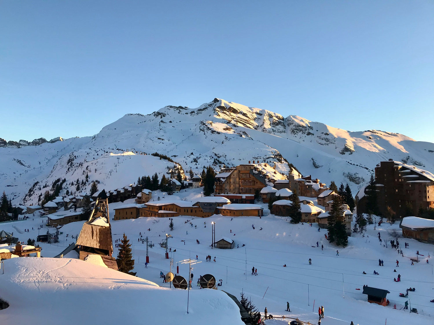 vue sur la station d'Avoriaz depuis les hauteurs, avec les montagnes enneigées et le levé du soleil